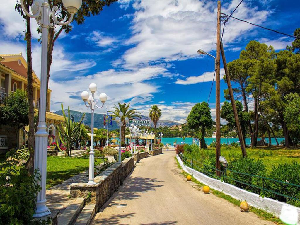 Pastaiga gar gleznainu ceļu ar teiksmainu ainavu, kur redzami koki, ziedi un mūsdienīgas laternas, kas izgaismo ceļu uz jūru. Skaists debesis ar mākoņiem veido ideālu fonu šim mierīgajam skatu punktam.