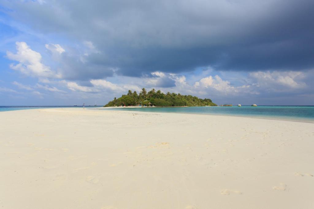 Tropu sala ar baltu smilšu pludmali un zilu ūdeni, apvīta ar mākoņainām debesīm. Ideāla vieta atpūtai un dabas baudīšanai.