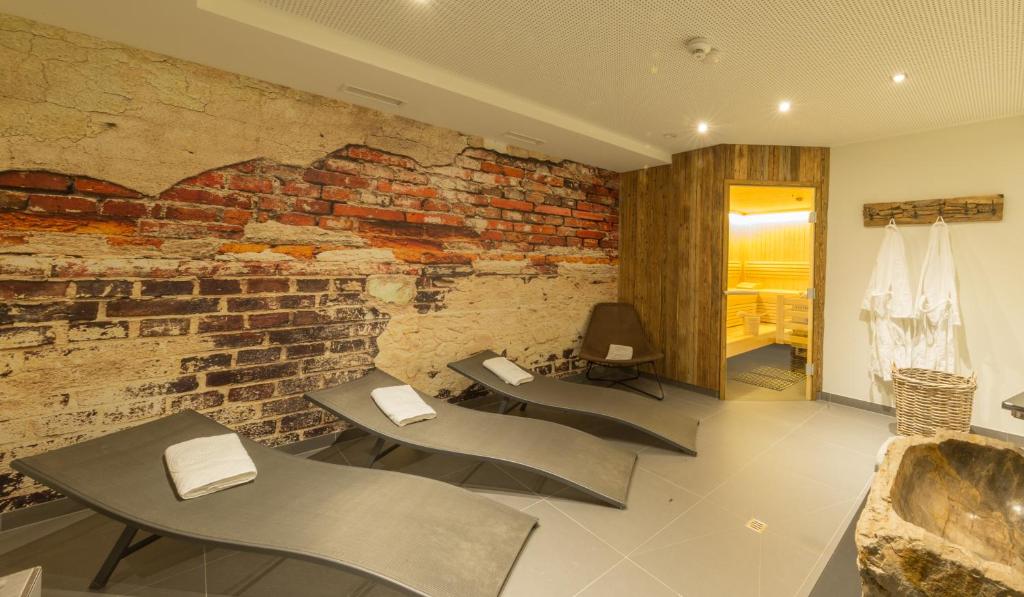 Atpūtas telpa ar mūsdienīgu dizainu, kas iekārtota ar ērtām atpūtas krēslām un siltu koka saunu fonā. Sienas rotātas ar ķieģeļu un mūra rakstu, radot relaksējošu atmosfēru.