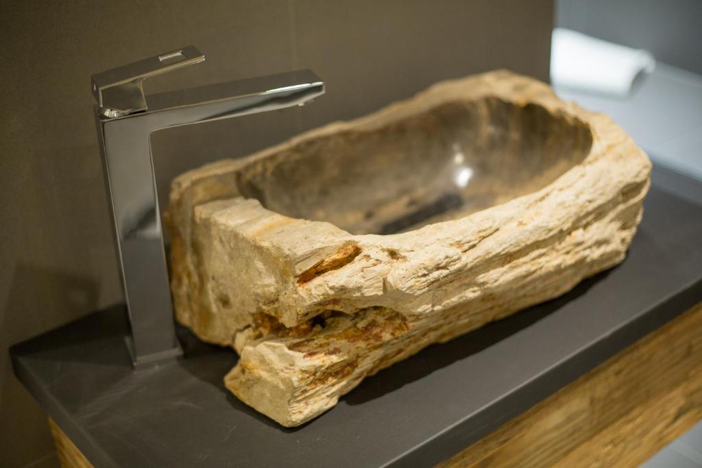 Dabīgā akmens izlietne ar modernu metāla jaucējkrānu, kas piešķir unikālu un stilīgu izskatu mūsdienu vannas istabai.