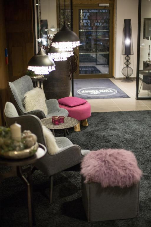 Mūsdienīga viesnīcas uzgaidāmā zona ar stilīgām mēbelēm, mīkstiem paklājiem un izsmalcinātām gaismām, radot siltu un viesmīlīgu atmosfēru.