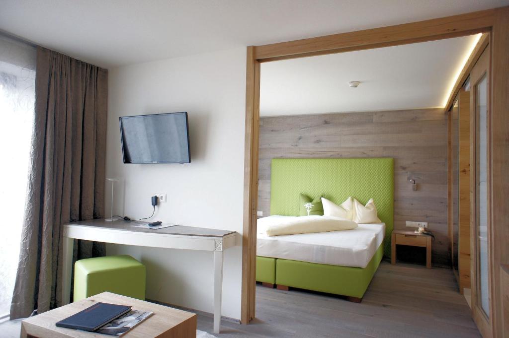 Mūsdienīgs viesnīcas numurs ar zaļu gultas galvu, televizoru pie sienas un rakstāmgaldu. Interjers ir gaišs un elegants, ar koka akcentiem un modernām mēbelēm.