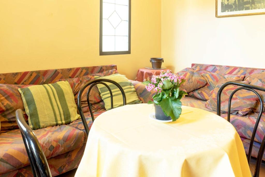 Mierīga viesistaba ar dīvāniem un galdu, uz kura atrodas ziedu pods. Sienas ir gaiši dzeltenas, un telpā ir daudz krāsu kombināciju.
