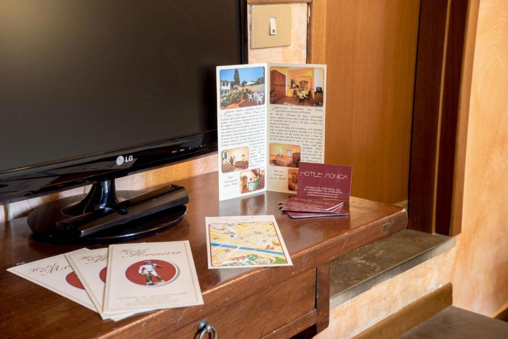 TV un viesnīcas bukleti uz koka galda, blakus ir kartes un vizītkartes. Vides elements, kas atspoguļo viesnīcas komfortu un viesu pakalpojumus.