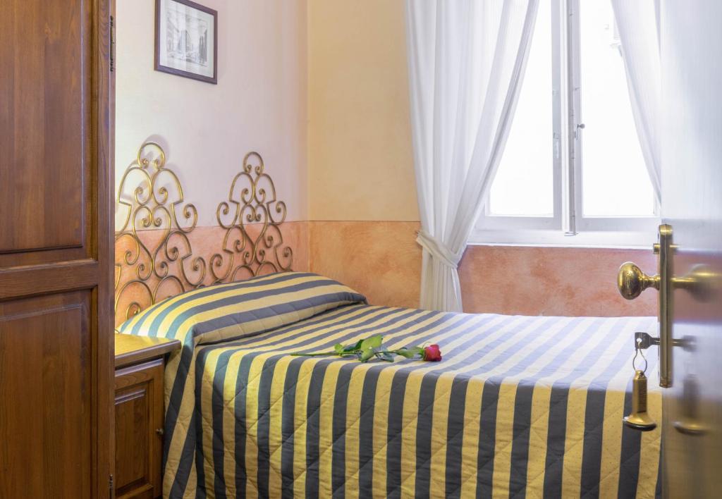 Kopta, kurā redzama jauka guļamistaba ar dzeltenām un zilām svītrām, greznu gultas galvu un rozēm uz gultas. Logi ar baltām aizkariem nodrošina dabisko apgaismojumu.