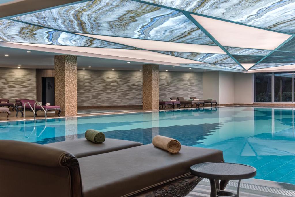 Mūsdienīgs iekštelpu peldbaseins ar elegantu dizainu, atpūtas krēsliem un stilīgu apgaismojumu. Šī relaksējošā vide ir ideāla vieta atpūtai un atjaunošanai.