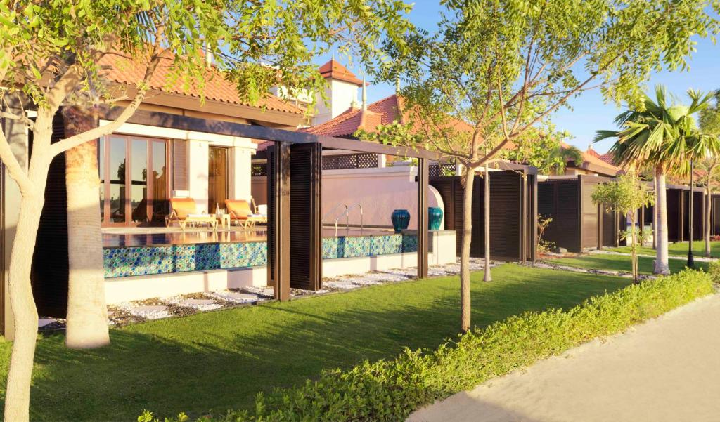 Mūsdienīga villa ar baseinu, kas ieskauta zaļā zālē un palmām, radot mierīgu un relaksējošu atmosfēru. Apskatāma ainava ar saulainu laiku un elegantiem dizaina elementiem.