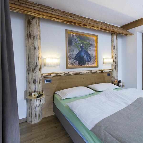 Mūsdienīgas guļamistabas interjers ar koka akcentiem, gultu un mākslas darbu uz sienas. Telpa ir gaiša un mājīga, radot relaksējošu atmosfēru.