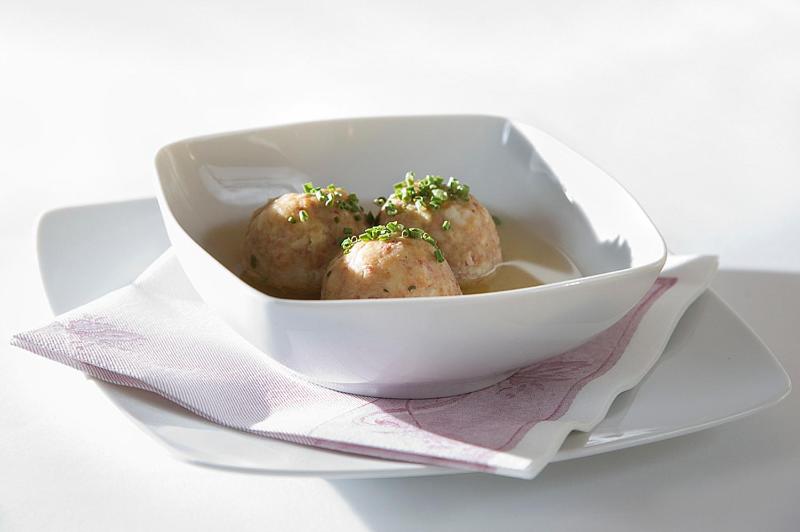 Svaigi pagatavoti gaļas bumbiņas, kas pasniegtas zupā, dekorētas ar zaļajiem sīpoliem.