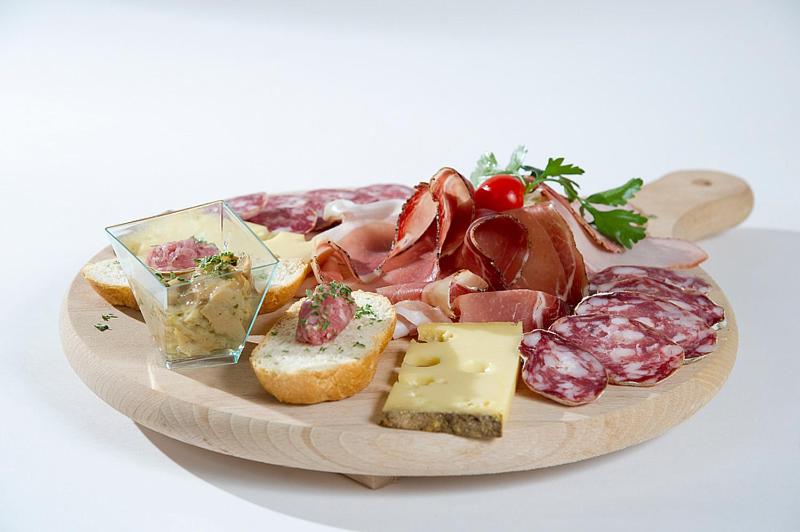 Siera un desiņu uzkodu plate ar maizītēm un mērci, rotāta ar tomātiem un zaļumiem.