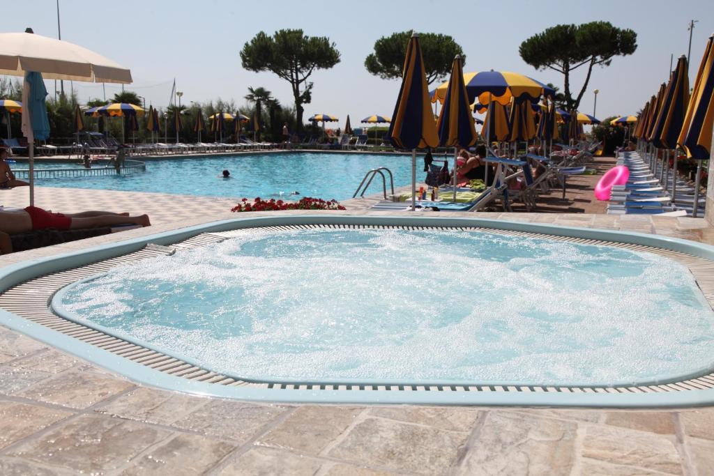 Baseins ar burbuļvannu un sauļošanās krēsliem, apkārtējā teritorija ar saules lietussargiem un cilvēkiem, kas atpūšas. Ideāla vieta relaksācijai un izklaidei.