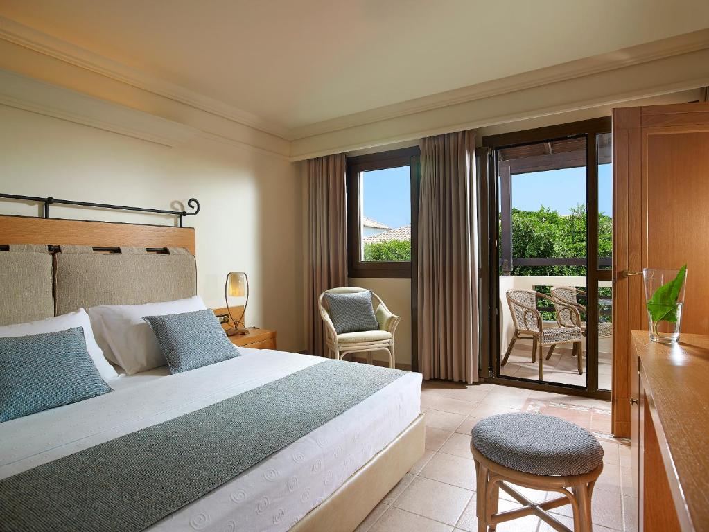 Moderns numurs viesnīcā Knossos Royal ar balkonu un dabu apkārt.