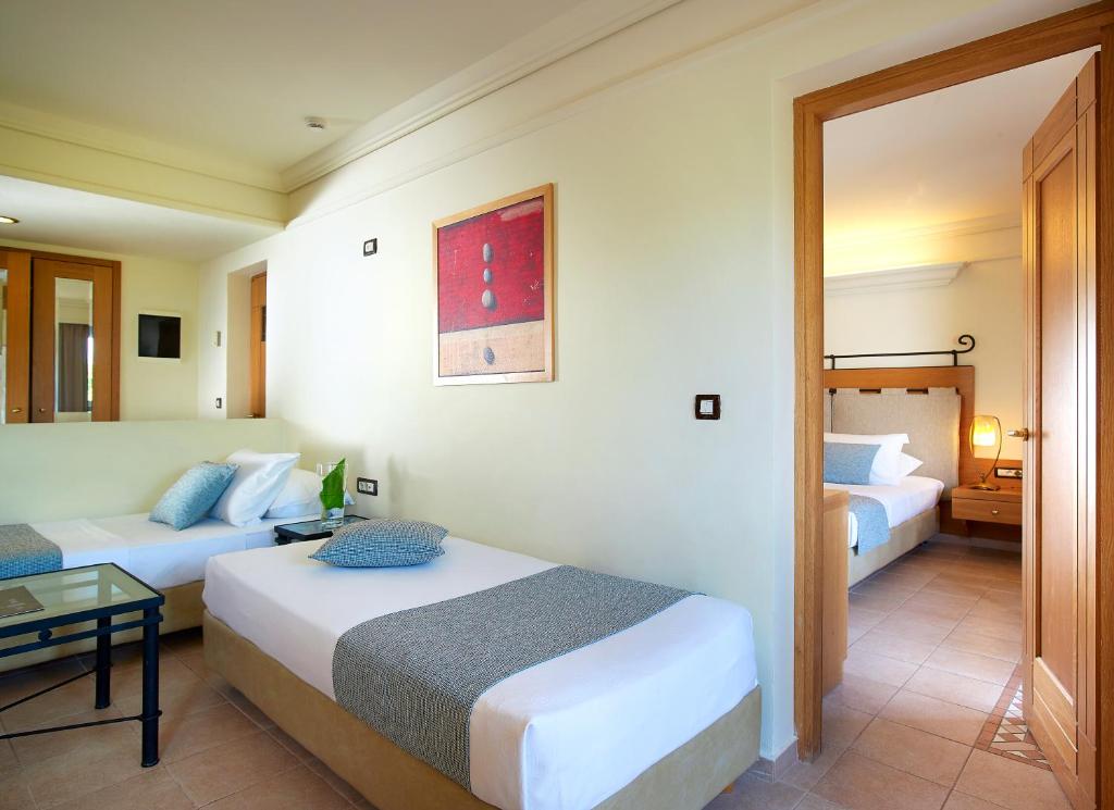 Viesnīcas Knossos Royal numurs ar divām gultām un mūsdienīgu interjeru.