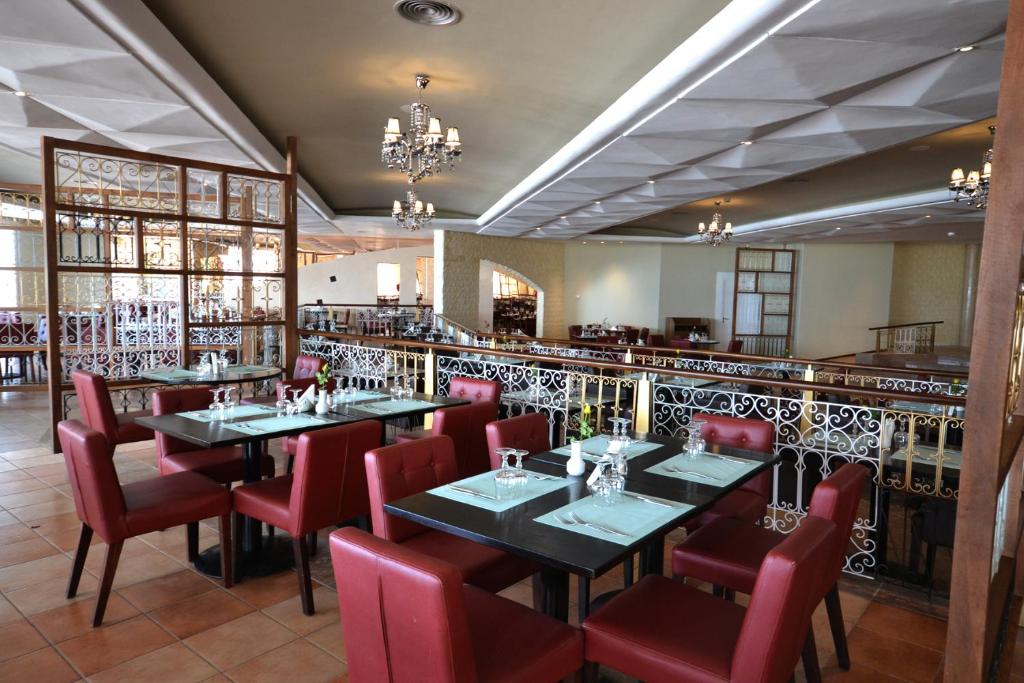 Mūsdienīgs restorāns ar elegantiem galdiem un sarkaniem krēsliem, kas piedāvā viesmīlīgu atmosfēru. Interjers iekārtots ar grezniem griestu lustriem un dekoratīvām detaļām.