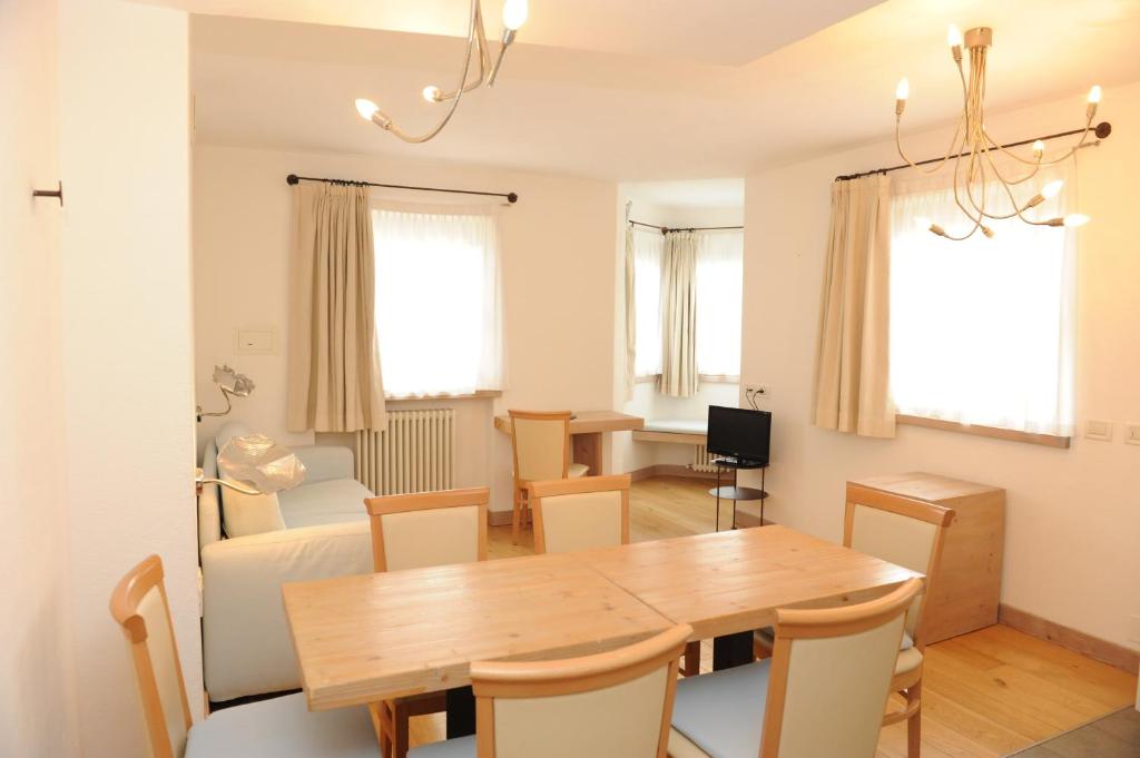 Gaiša un mājīga dzīvojamā istaba ar koka galdu un krēsliem, dīvānu un televizoru. Labi apgaismota telpa ar logiem, kas nodrošina dabisko gaismu.