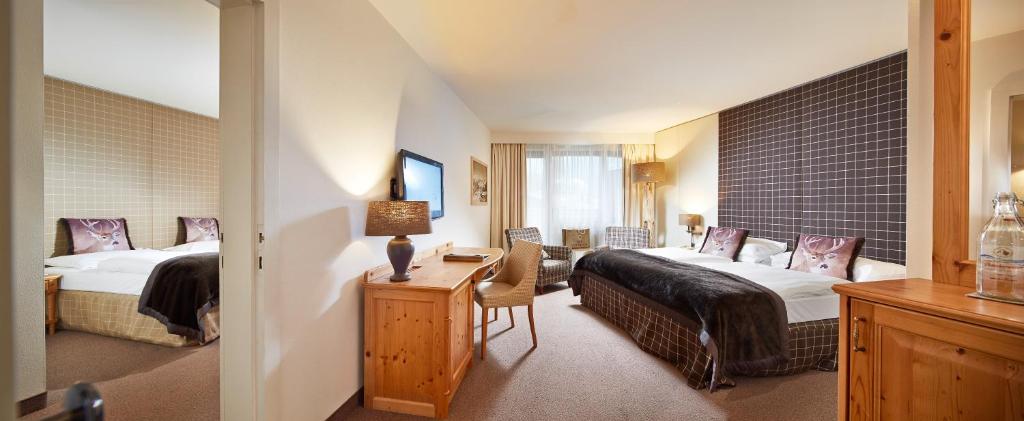 Mūsdienīgs viesnīcas numurs ar divām gultām, koka mēbelēm un ērtām sēdvietām. Telpa ir gaiša un plaša, ar logiem, kas nodrošina dabisko apgaismojumu.