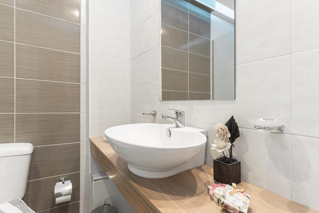 Mūsdienīga un eleganta vannas istaba ar baltu izlietni un koka virsmu, dekorēta ar smalkiem aksesuāriem. Svaigs un tīrs interjers ar neitrālām krāsām.