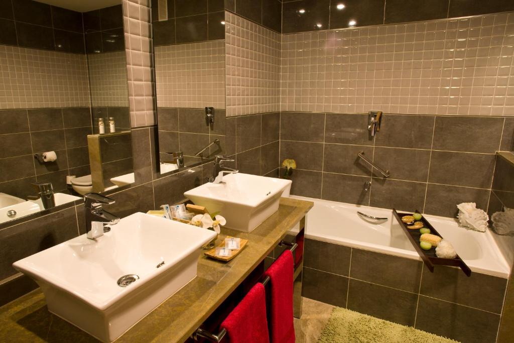 Mūsdienīga vannas istaba ar diviem izlietnēm, vannu un elegantu apgaismojumu, veidota ar pelēku flīžu un akmens detaļām. Vannas istabā ir arī dekoratīvi elementi, kas piešķir mājīgumu.