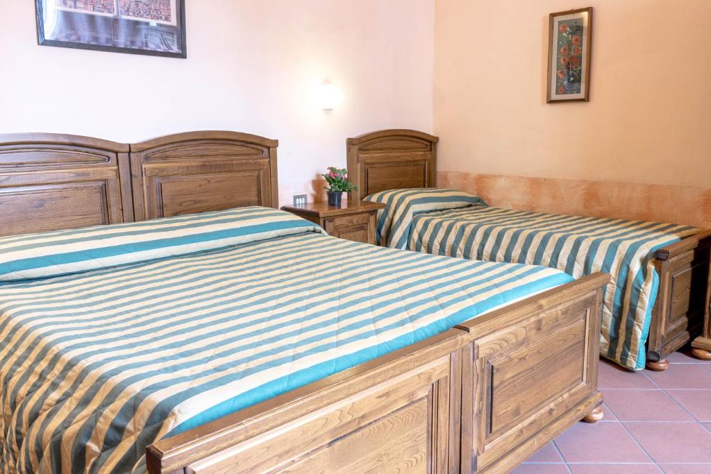 Guļamistaba ar divām gultām, kas pārklātas ar svītrainām gultasveļām, un koka mēbelēm. Telpā ir arī dekoratīvs elements uz sienas un neliela podiņa ar ziediem uz naktsgaldiņa.