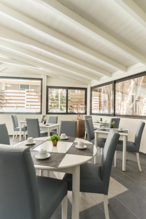 Mūsdienīgs un gaišs restorāna interjers ar baltām sienām un koka griestiem. Galdi ir sakārtoti ar pelēkiem krēsliem un dekoratīviem elementiem uz galda.