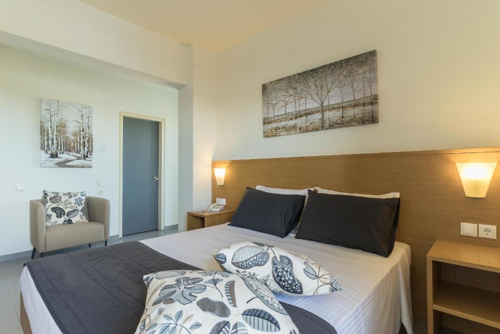 Mūsdienīga viesnīcas numura iekārtojums ar ērtu gultu, dekoratīvām spilveniem un mākslas darbiem uz sienām, radot patīkamu un relaksējošu atmosfēru.