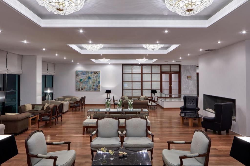 Mūsdienīgs viesnīcas interjers ar elegantu mēbeļu izkārtojumu, gaismas lustru un mākslas darbu. Plaša telpa ar koka grīdu un relaksējošu atmosfēru.