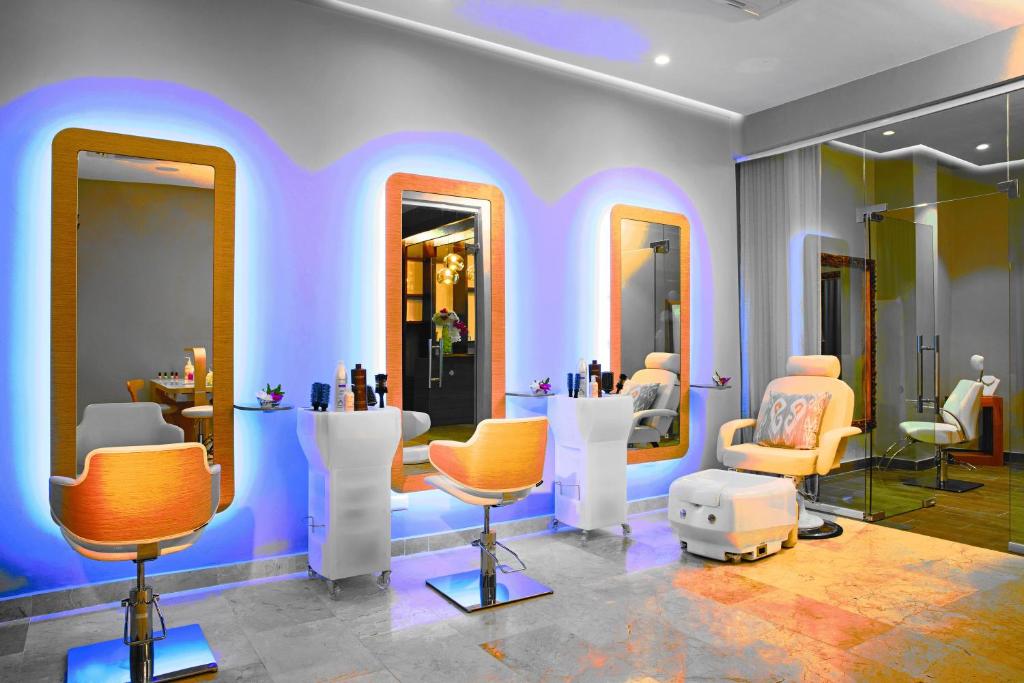 Mūsdienīgs frizētavas interjers ar stilīgām spoguļiem un krēslām, kas apgaismoti ar krāsainām gaismām, radot patīkamu atmosfēru. Ideāli piemērots relaksējošām skaistumkopšanas procedūrām.