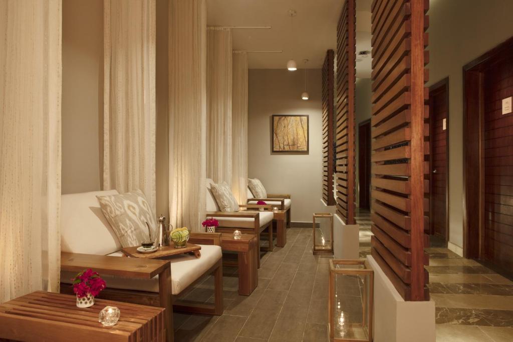 Mūsdienīgs spa atpūtas telpa ar koka mēbelēm, ērtiem krēsliem un maigu apgaismojumu, radot relaksējošu atmosfēru. Interjeru papildina dekoratīvi elementi un ziedi uz galdiņiem.