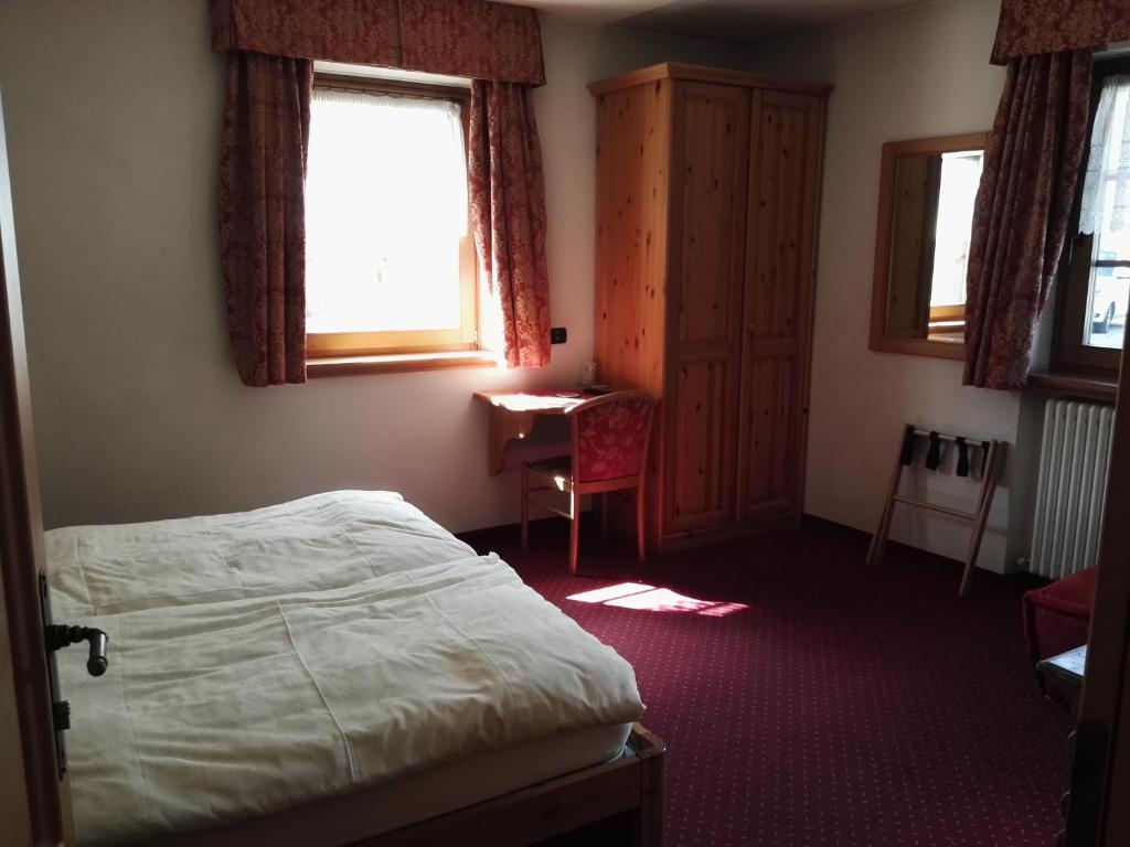 Maza viesnīcas istaba ar divguļamo gultu, koka skapjiem un rakstāmgaldu. Logi nodrošina dabīgu apgaismojumu, radot mājīgu atmosfēru.