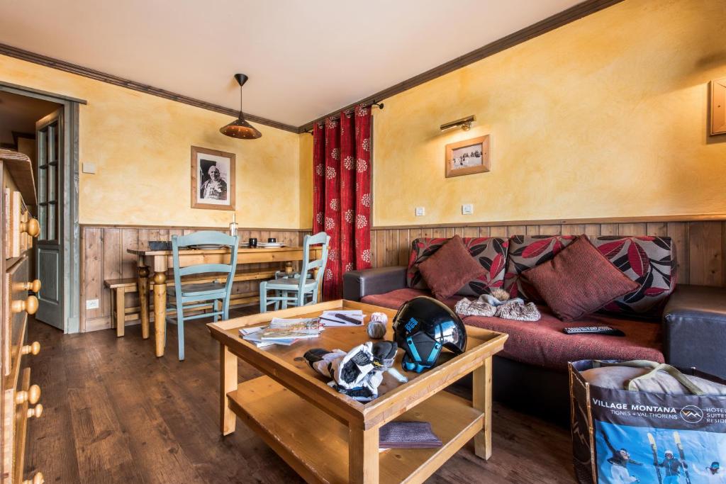 Mūsdienīgs viesistabas interjers ar koka mēbelēm, sarkanu aizkaru un mākslas darbu pie sienas, radot siltu un mājīgu atmosfēru.