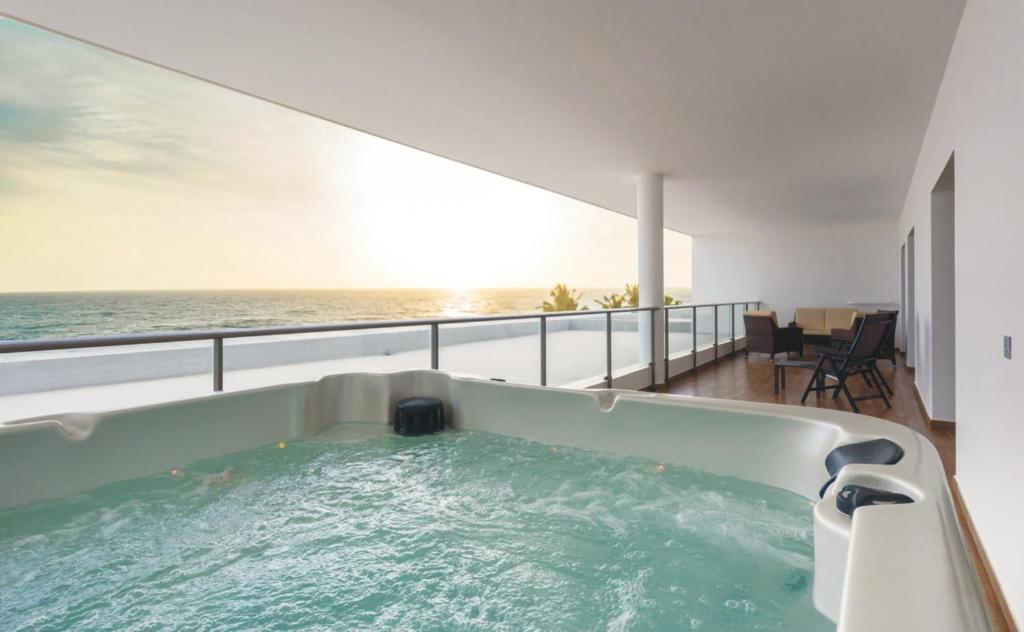 Terase ar džakuzi, skats uz jūru un saulrietu, mūsdienīgs dizains un komfortabla atpūtas zona.