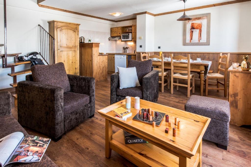 Mūsdienīga un mājīga viesistaba ar brūniem krēsliem, koka galdu un virtuvīti. Telpa ir gaiša un ērta, piemērota relaksācijai vai ģimenes vakariem.