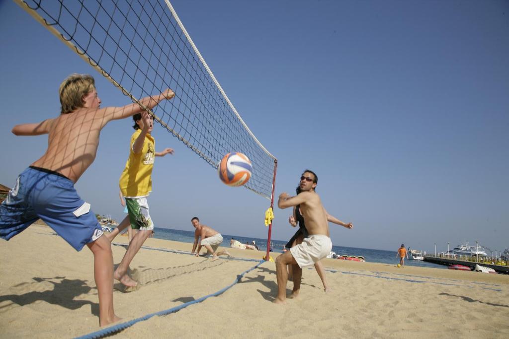 Vīrieši spēlē pludmales volejbolu SUNRISE Royal Makadi Resort pludmalē.