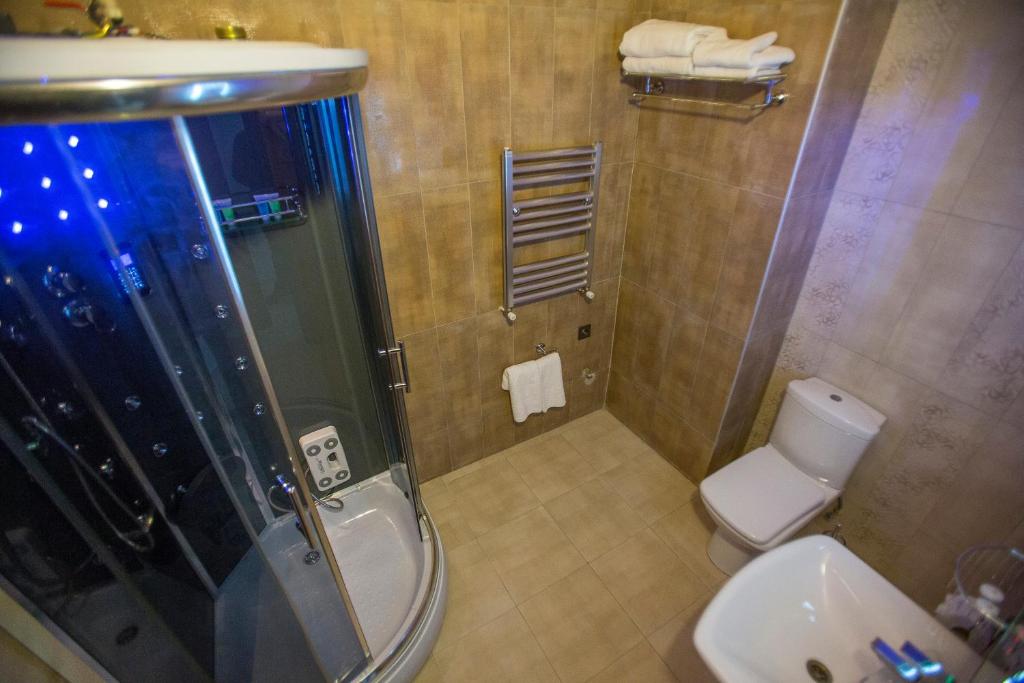Mūsdienīga vannas istaba ar dušas kabīni, siltumu regulējošu radiatoru un baltu tualeti. Telpa ir veidota ar mūsdienīgu apdari un ir labi apgaismota.