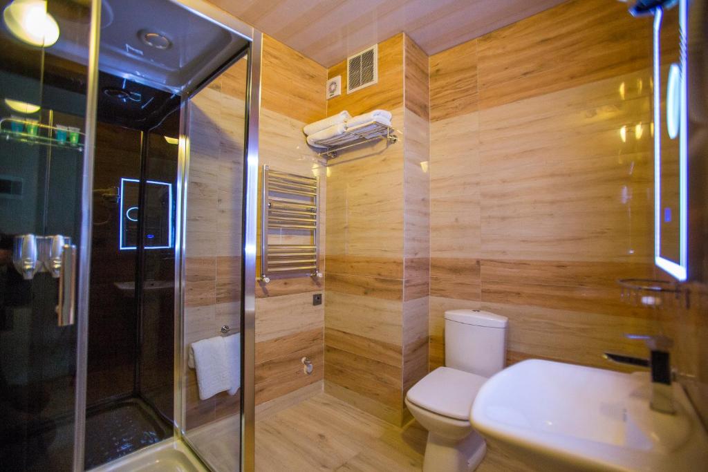 Mūsdienīga vannas istaba ar dušas kabīni, tualeti un izsmalcinātu koka apdari. Telpa ir gaiša un eleganta, radot komfortablu atmosfēru.