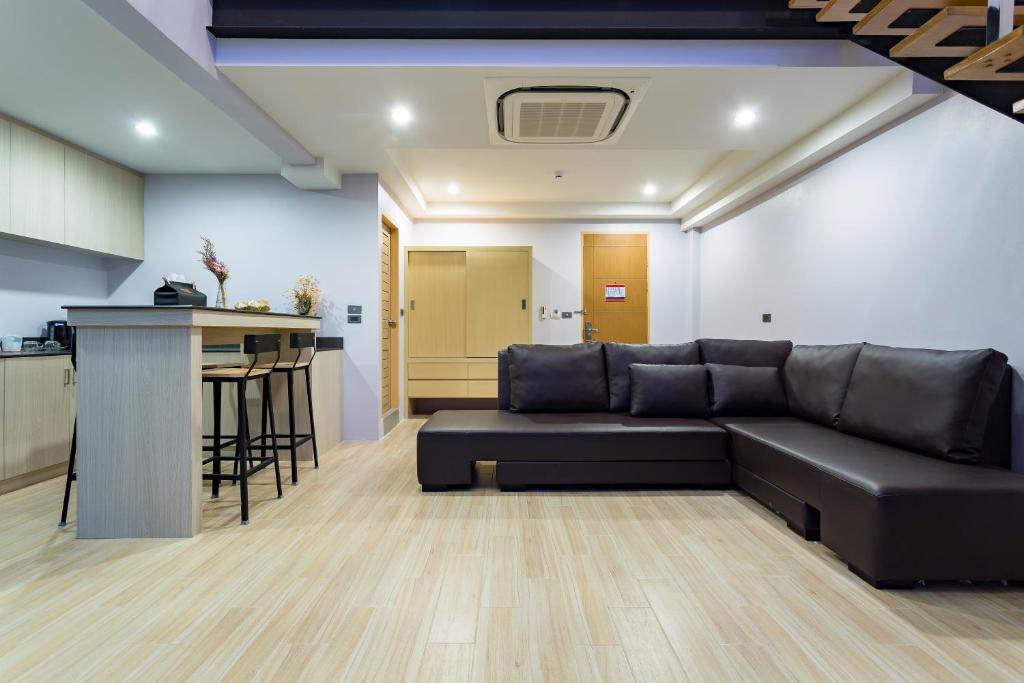 Mūsdienīga viesistaba ar ērtu tumšu dīvānu, koka grīdu un nelielu virtuves zonu, kas iekārtota ar bāra leti un krēsliem. Interjers ir gaišs un funkcionāls, radot mājīgu atmosfēru.