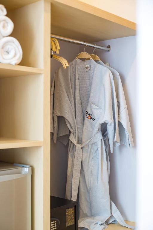 Elegants viesnīcas halāts un salocītas dvieļi, kas glabājas skapī. Halāts ir gaiši zils ar logo.