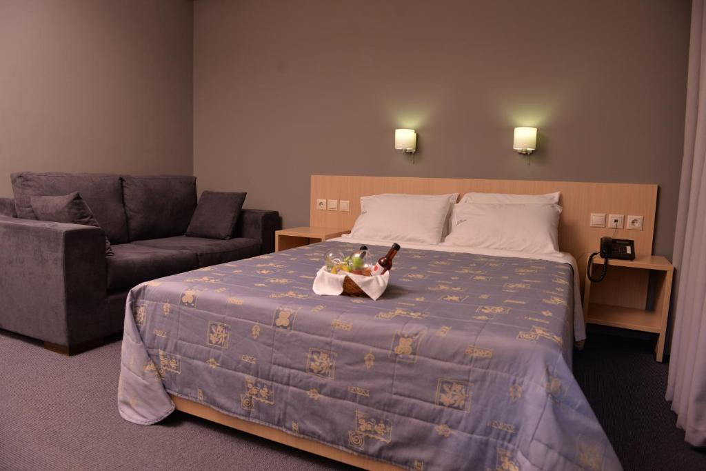 Mūsdienīga viesnīcas numura iekārtojums ar divguļamo gultu un atpūtas zonu. Uz gultas redzama uzkodu plate ar dzērieniem.