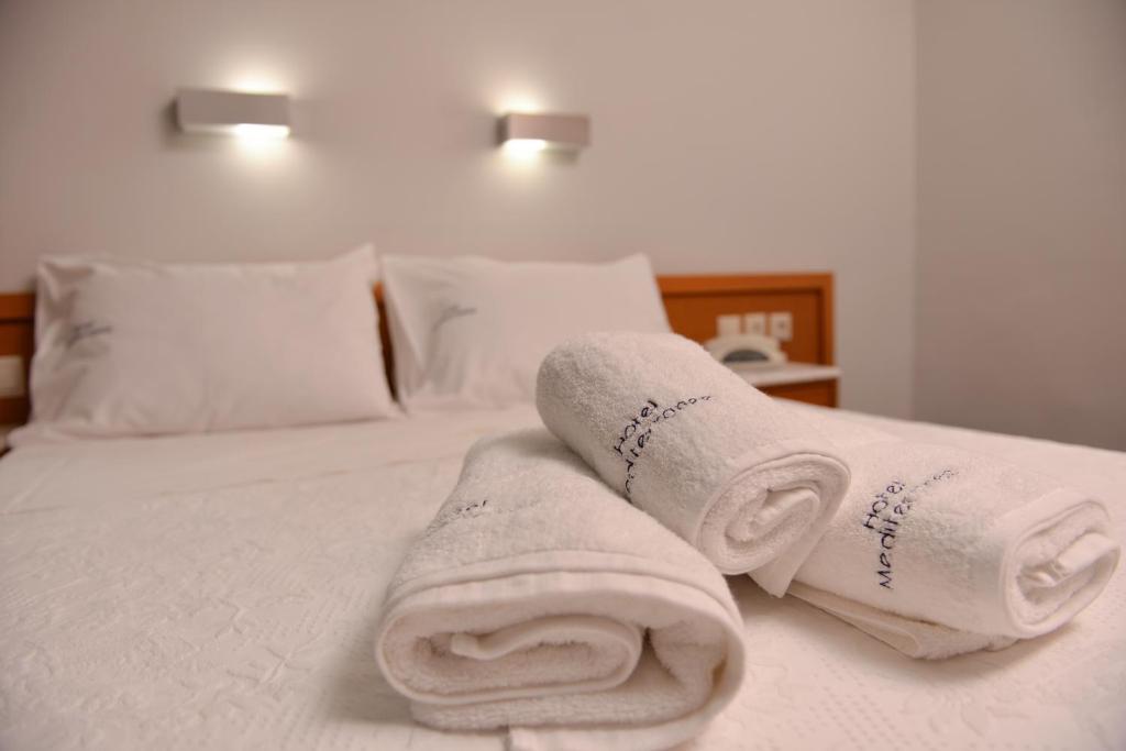 Gultas veļa un balti dvieļi viesnīcas numurā, ar maigu apgaismojumu. Komfortabla un relaksējoša atmosfēra.