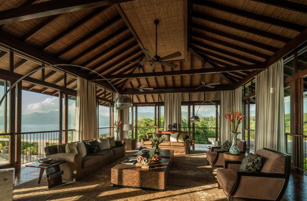 Plaša Four Seasons Resort Seychelles villas viesistaba ar panorāmas skatu uz piekrasti.