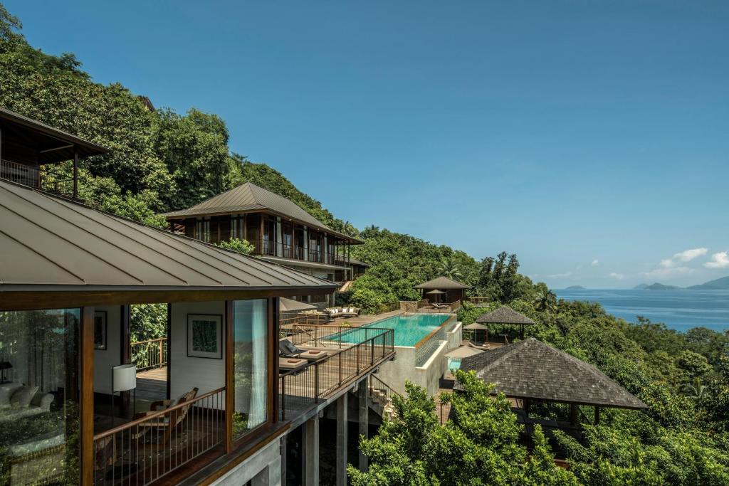 Four Seasons Resort Seychelles privātās villas ar baseinu un skatu uz okeānu zaļā piekrastē.