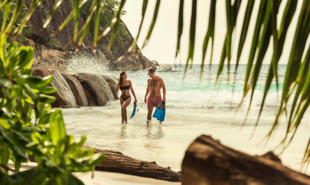 Pāris ar snorkelēšanas aprīkojumu iznāk no ūdens Four Seasons Resort Seychelles pludmalē.