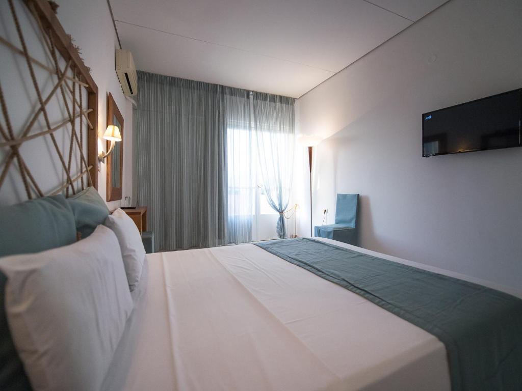 Mūsdienīga viesnīcas numuriņa interjers ar gultu, gaišām krāsām un logu, caur kuru ieplūst dabiska gaisma. Numurā ir televizors un ērta sēdvieta.