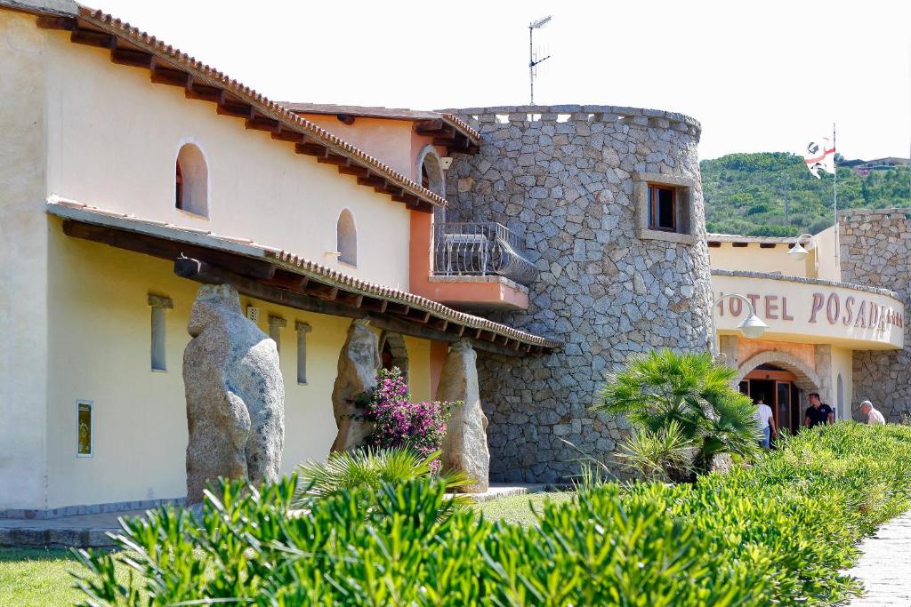 Viesnīcas "Posada" ēka ar akmens elementiem un dārzu, kas rotāts ar ziediem un zaļumiem. Ievērību pievērš arī blakus esošie akmens skulptūras.