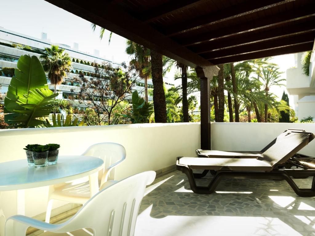 Balconā redzama brīnišķīga tropiskā ainava ar zaļiem augiem un palmām, kā arī atpūtas krēslām un galdu, kas ir ideāli piemēroti relaksācijai.