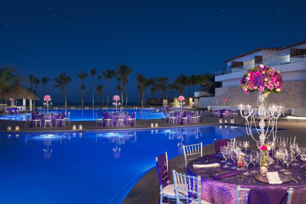 Eleganti dekorēts baseins ar ziedu kompozīcijām un gaismas elementiem, kas rada romantisku atmosfēru nakts laikā. Ideāla vieta kāzām vai svinībām pie ūdens.