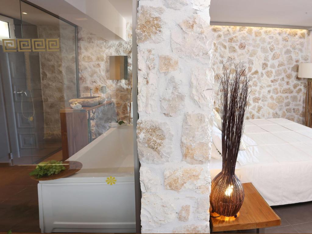 Mūsdienīga guļamistaba ar akmens sienu, stikla dušu un vannu, kā arī dekoratīvu lampu un augu akcentiem. Ideāla vieta relaksācijai un komfortam.