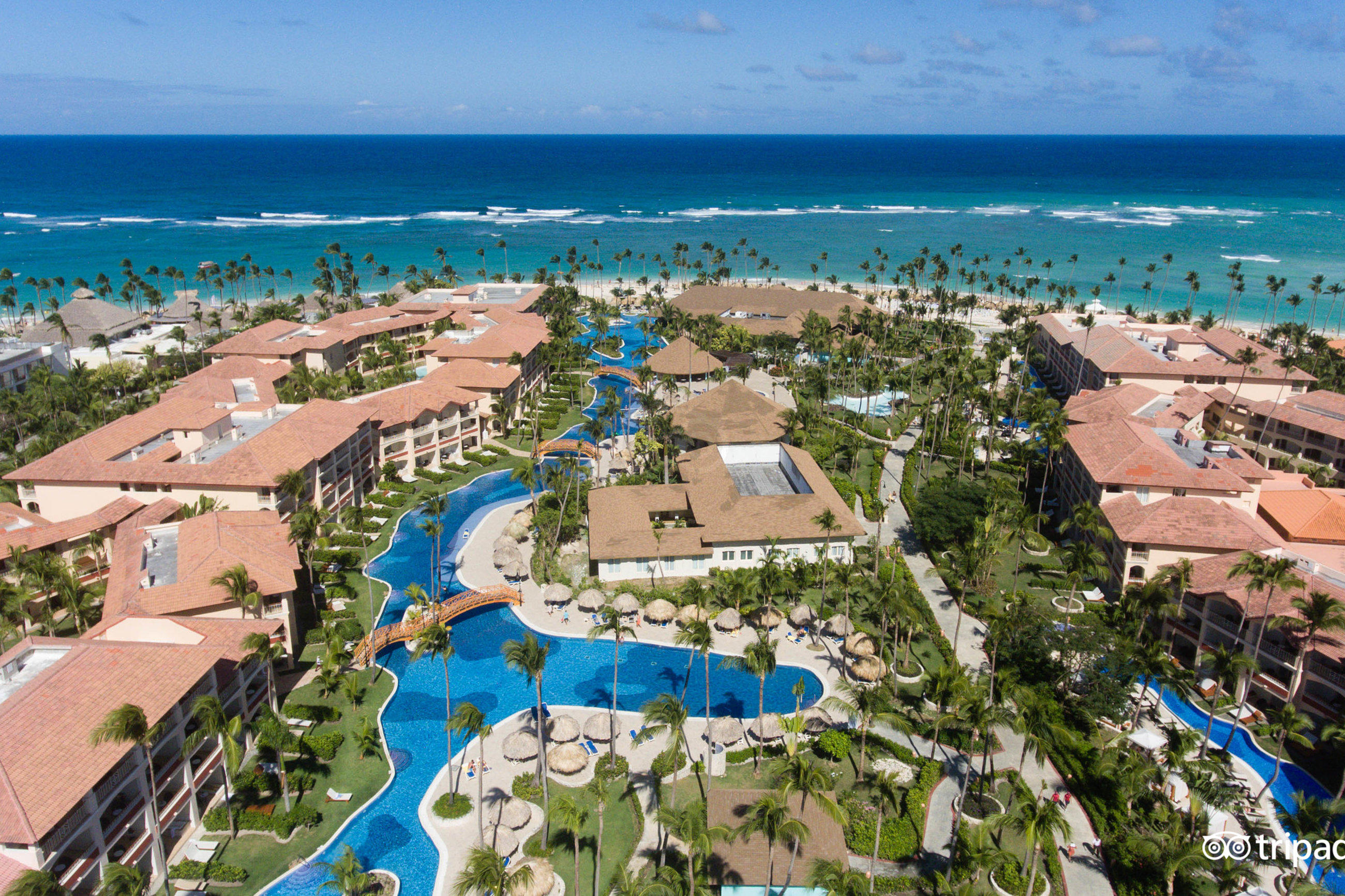 Viesnīcas komplekss pie okeāna ar skaistām peldbaseinu zonām un palmām. Ideāla atpūtas vieta ar tropisku ainavu un piekļuvi pludmalei. panoramic view with beach and pools