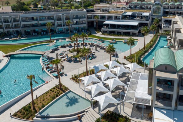Mūsdienīgs kūrorts ar peldbaseiniem un palmām, kas piedāvā relaksējošu atpūtu. Plašs teritorijas dizains ar saulessargiem un atpūtas zonām. panoramic view with beach and pools