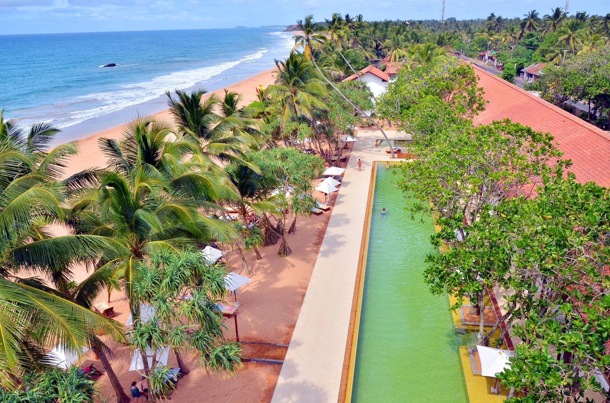 Tropu pludmale ar palmām un mierīgu ūdenstilpni, kas piedāvā relaksējošu atmosfēru. Svaigs jūras gaiss un saulains laiks veido ideālu atpūtas vietu. panoramic view with beach and pools